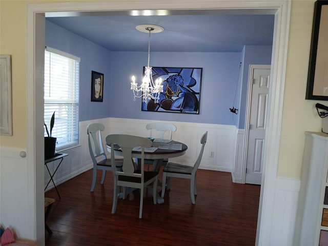 dining area featuring dark wood-style floors, a wainscoted wall, and a notable chandelier