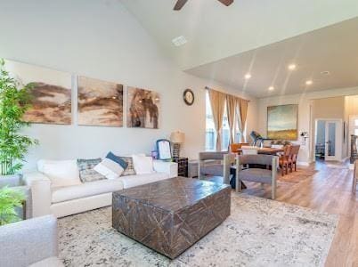 living room with hardwood / wood-style floors, ceiling fan, and high vaulted ceiling