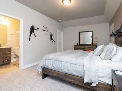 carpeted bedroom with ensuite bathroom and vaulted ceiling