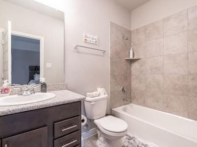 full bathroom featuring tiled shower / bath, vanity, and toilet