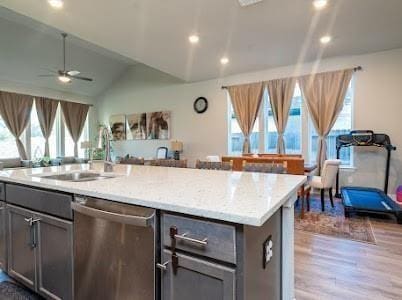 kitchen with dishwasher, lofted ceiling, a center island with sink, sink, and ceiling fan