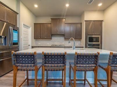 kitchen featuring tasteful backsplash, an island with sink, and appliances with stainless steel finishes