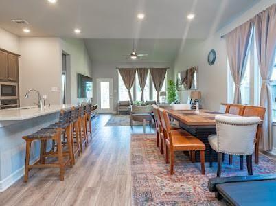 dining area featuring ceiling fan, light hardwood / wood-style floors, lofted ceiling, and sink