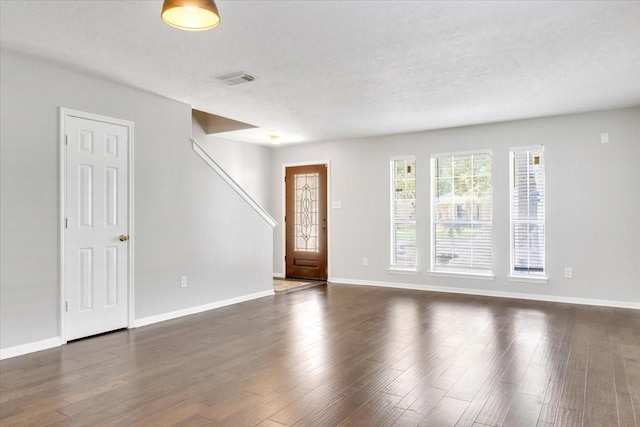 unfurnished room with a textured ceiling and dark wood-type flooring