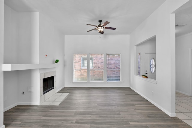 unfurnished living room with a tile fireplace and ceiling fan