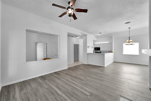 unfurnished living room featuring light hardwood / wood-style flooring and ceiling fan with notable chandelier