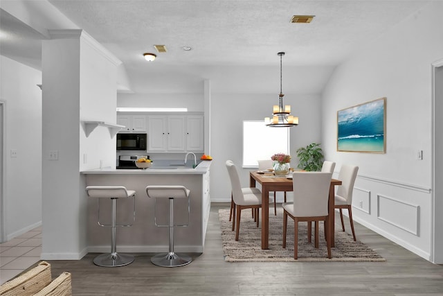 dining area featuring a textured ceiling, dark hardwood / wood-style floors, an inviting chandelier, and lofted ceiling