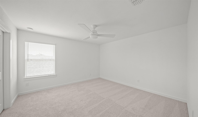 carpeted spare room featuring ceiling fan, visible vents, and baseboards