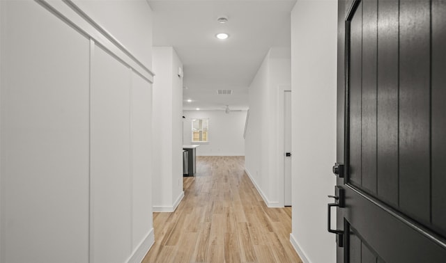 corridor with light wood finished floors, recessed lighting, visible vents, and baseboards