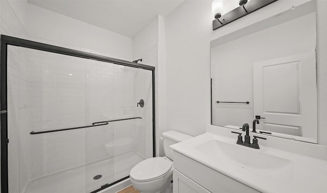 bathroom with a shower with door, vanity, and toilet