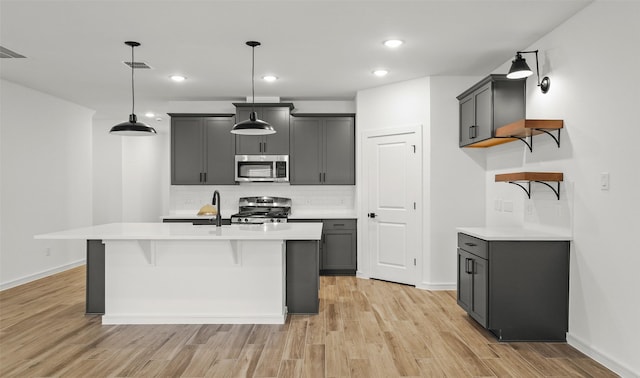 kitchen featuring light hardwood / wood-style flooring, decorative light fixtures, decorative backsplash, gray cabinets, and appliances with stainless steel finishes