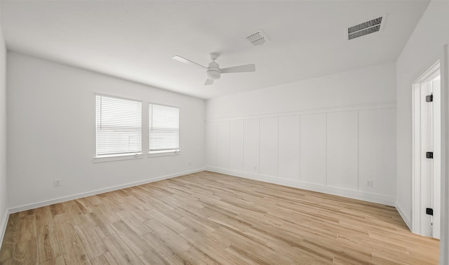 spare room featuring light wood-style floors, baseboards, visible vents, and a ceiling fan