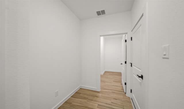 corridor featuring light wood-type flooring, baseboards, and visible vents