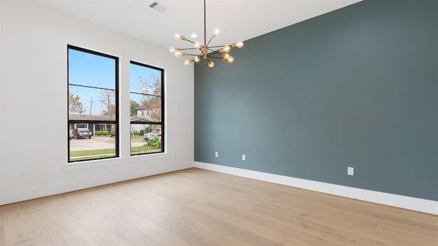 unfurnished room with light wood-type flooring and a notable chandelier