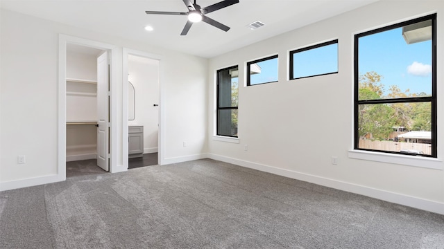 unfurnished bedroom featuring carpet flooring, a spacious closet, multiple windows, and ceiling fan