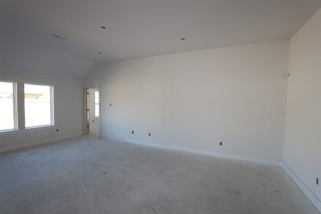 empty room featuring unfinished concrete flooring, baseboards, and vaulted ceiling