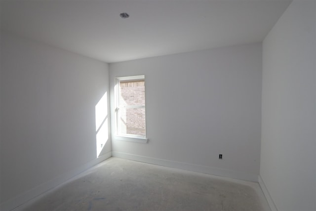 unfurnished room with unfinished concrete floors and baseboards