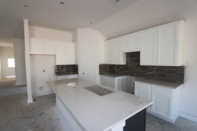 kitchen with decorative backsplash, lofted ceiling, a kitchen island, and white cabinets