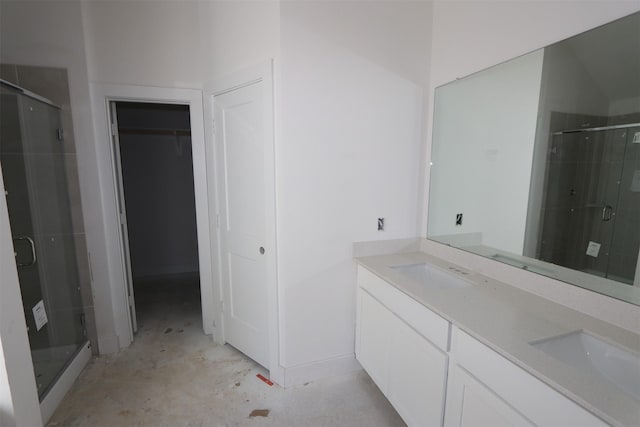 full bathroom with concrete floors, double vanity, a stall shower, a sink, and a walk in closet