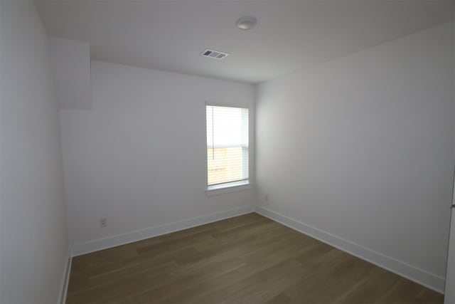 spare room with baseboards, wood finished floors, and visible vents