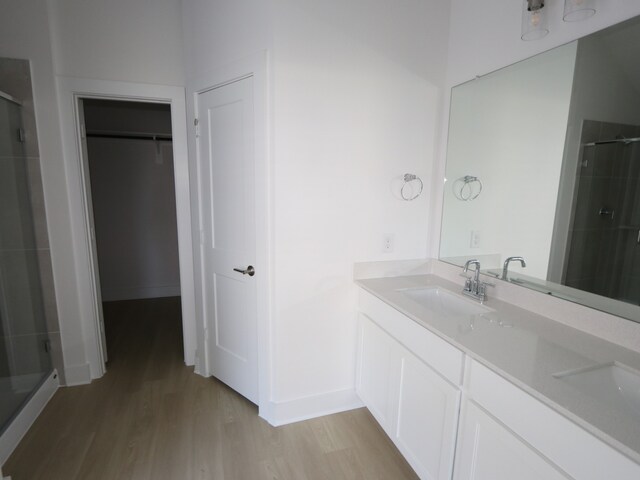 8622 Sun Coral Dr, Cypress, TX 77433 - bathroom with a sink, wood finished floors, a spacious closet, a shower stall, and baseboards