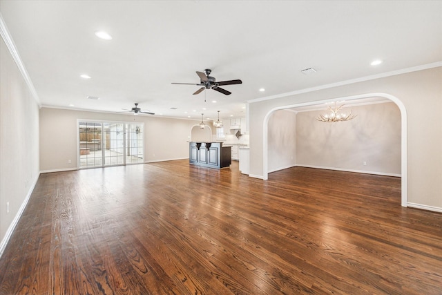 unfurnished living room with ceiling fan with notable chandelier, dark hardwood / wood-style floors, and crown molding