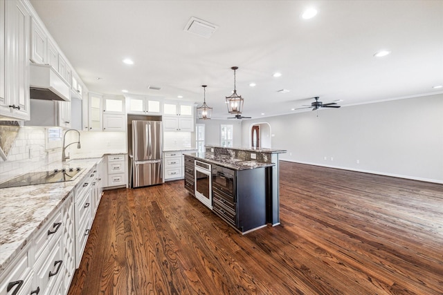 kitchen featuring white cabinets, stainless steel fridge, black electric cooktop, light stone counters, and dark hardwood / wood-style flooring