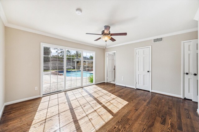 empty room featuring ceiling fan, ornamental molding, and dark wood-type flooring