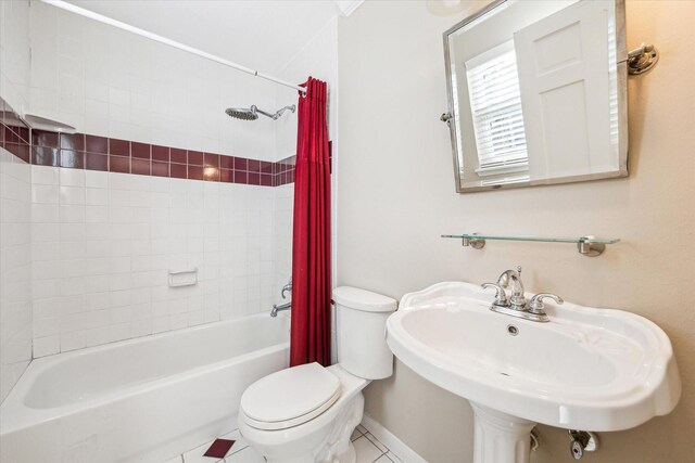 full bathroom with tile patterned floors, shower / bath combo with shower curtain, sink, and toilet