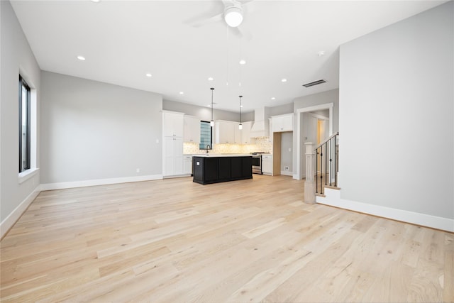 unfurnished living room featuring sink, ceiling fan, and light wood-type flooring