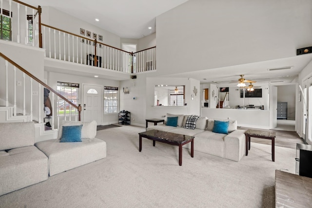 carpeted living room with ceiling fan and a high ceiling