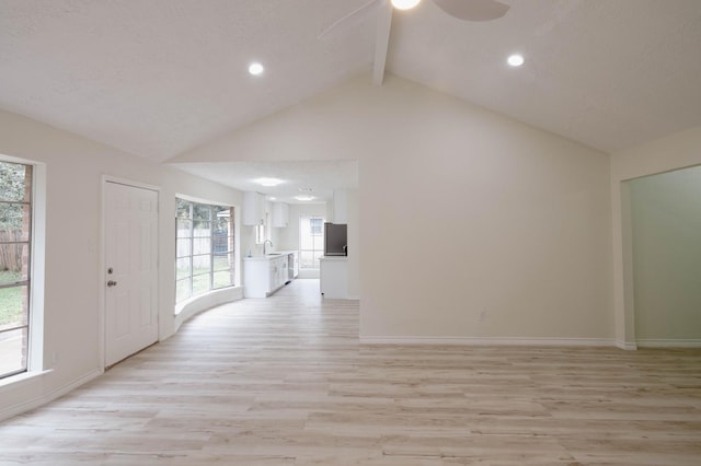 interior space featuring a wealth of natural light, light hardwood / wood-style flooring, beamed ceiling, and sink