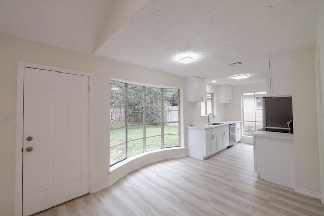 kitchen with light wood-type flooring, stainless steel appliances, white cabinetry, and sink