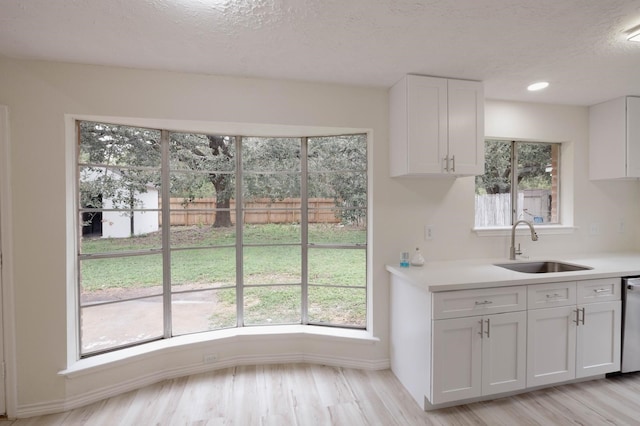 kitchen featuring light hardwood / wood-style floors, white cabinetry, sink, and a wealth of natural light