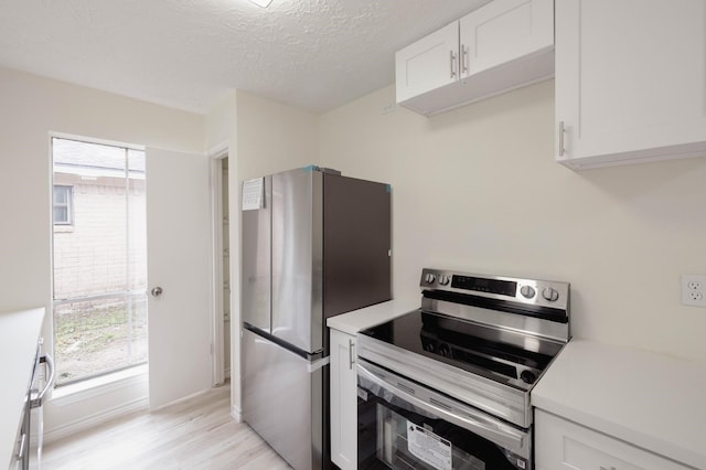 kitchen featuring appliances with stainless steel finishes, a textured ceiling, light hardwood / wood-style floors, and white cabinetry