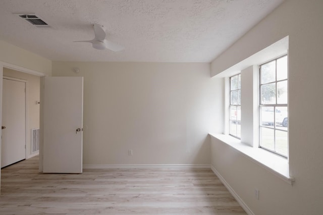 empty room featuring a textured ceiling, light hardwood / wood-style flooring, and ceiling fan