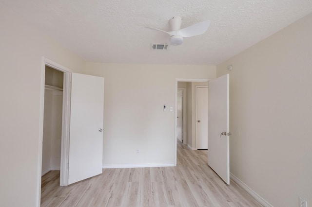 unfurnished bedroom with ceiling fan, a closet, a textured ceiling, and light wood-type flooring