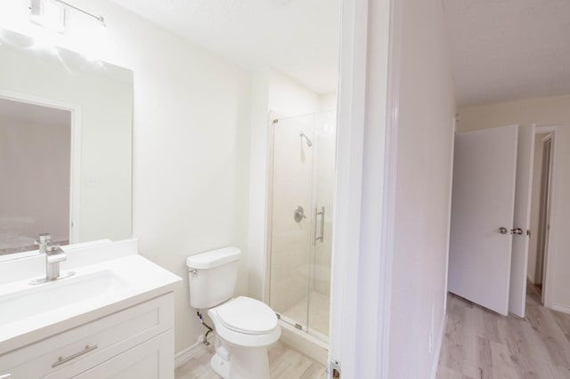 bathroom with hardwood / wood-style floors, vanity, toilet, and a shower with door