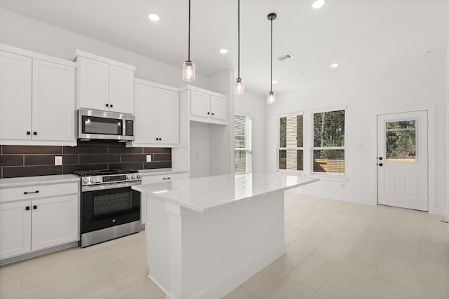 kitchen featuring light stone counters, white cabinetry, visible vents, appliances with stainless steel finishes, and decorative backsplash