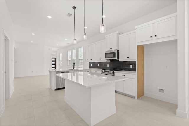 kitchen with tasteful backsplash, visible vents, a kitchen island, a peninsula, and stainless steel appliances