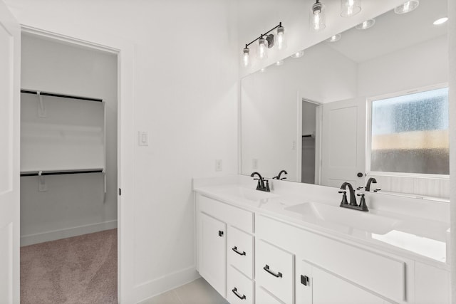 full bathroom featuring double vanity, a sink, and a walk in closet