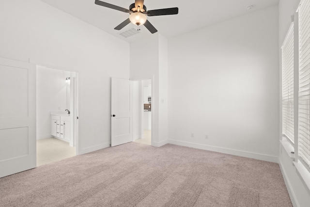 unfurnished bedroom featuring a high ceiling, multiple windows, carpet, and visible vents