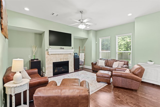 living room featuring a fireplace, ceiling fan, and dark wood-type flooring