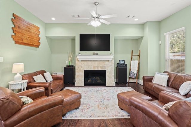 living room with ceiling fan, wood-type flooring, and a tiled fireplace