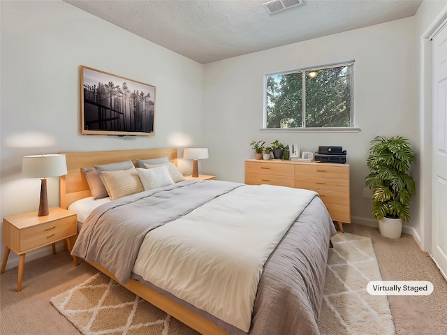 bedroom featuring light colored carpet and a textured ceiling