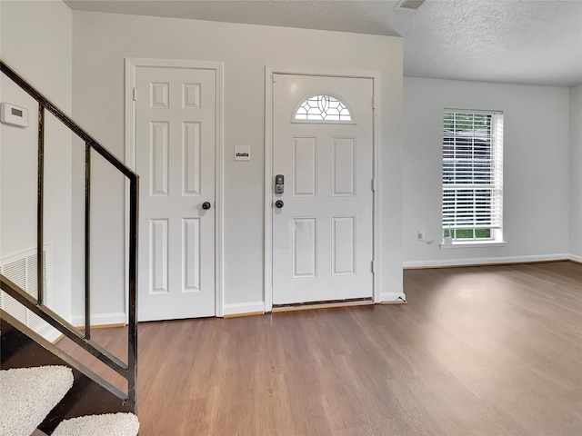 foyer with a textured ceiling and light hardwood / wood-style flooring