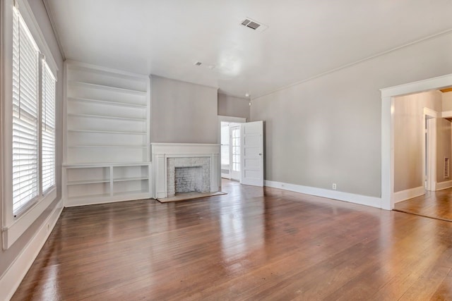 unfurnished living room featuring built in shelves and dark hardwood / wood-style flooring