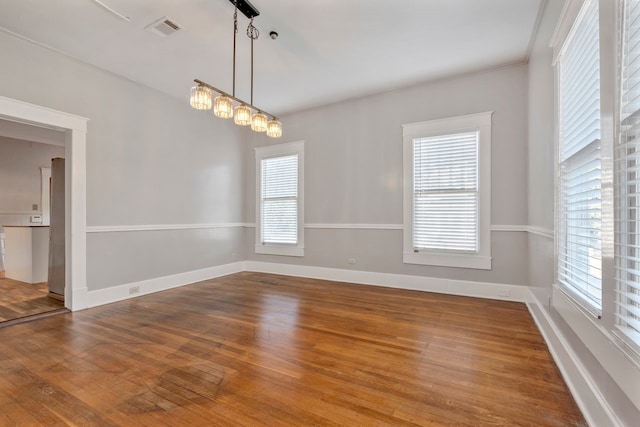 spare room featuring hardwood / wood-style flooring and a chandelier