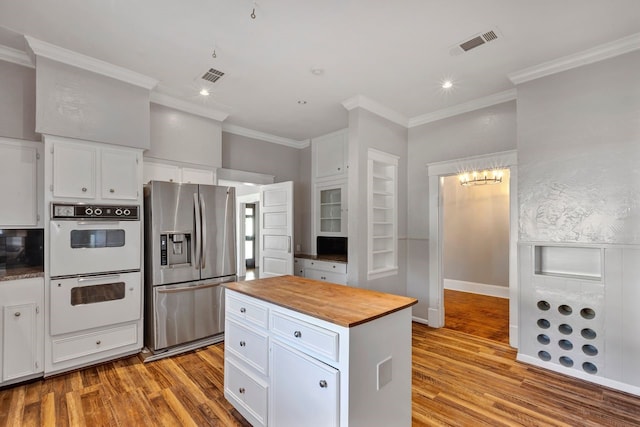 kitchen with white cabinets, light hardwood / wood-style floors, white double oven, and stainless steel refrigerator with ice dispenser