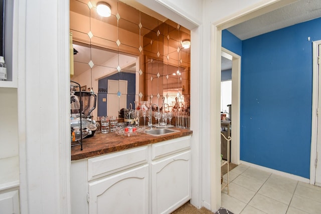 bar featuring white cabinets, light tile patterned floors, butcher block counters, and sink